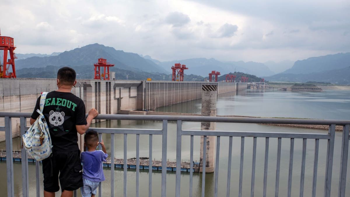 A father and son survey low water levels at the Three Gorges Dam along China's Yangtze River