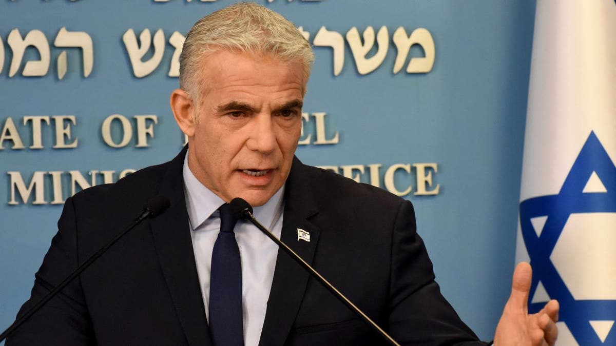 Israeli Prime Minister Yair Lapid speaks at press conference wearing black suit and blue tie