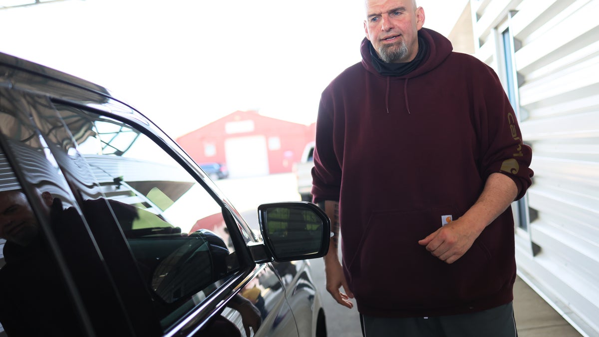 John Fetterman walks near a car