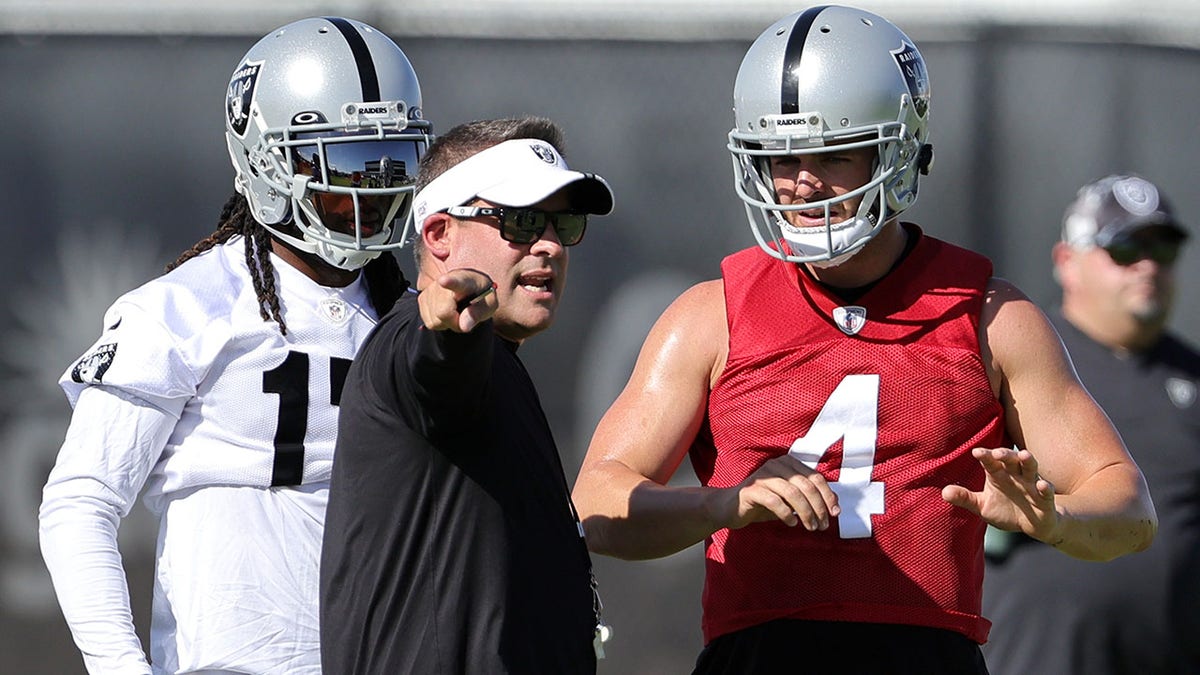 Raiders head coach Josh McDaniels talks with quarterback Derek Carr