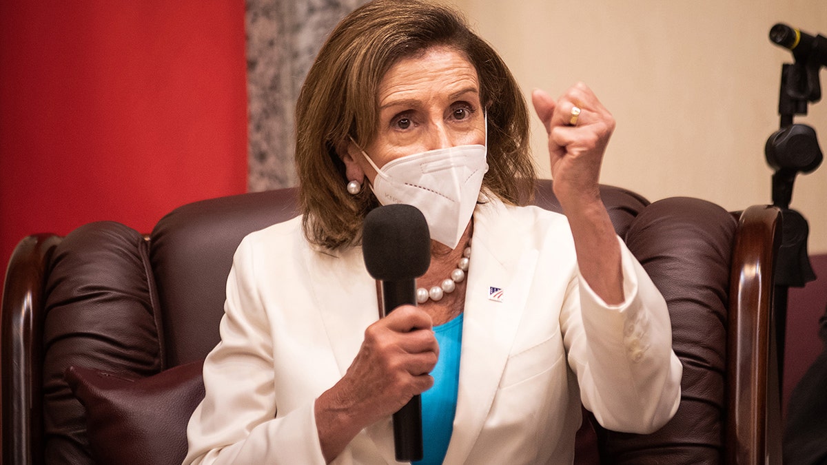 Pelosi holding making a fist with a microphone in her other hand
