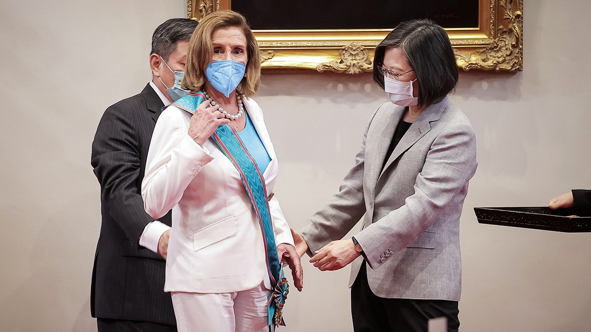 Nancy Pelosi seen with Taiwan officials in a white pantsuit with a sash Taiwan