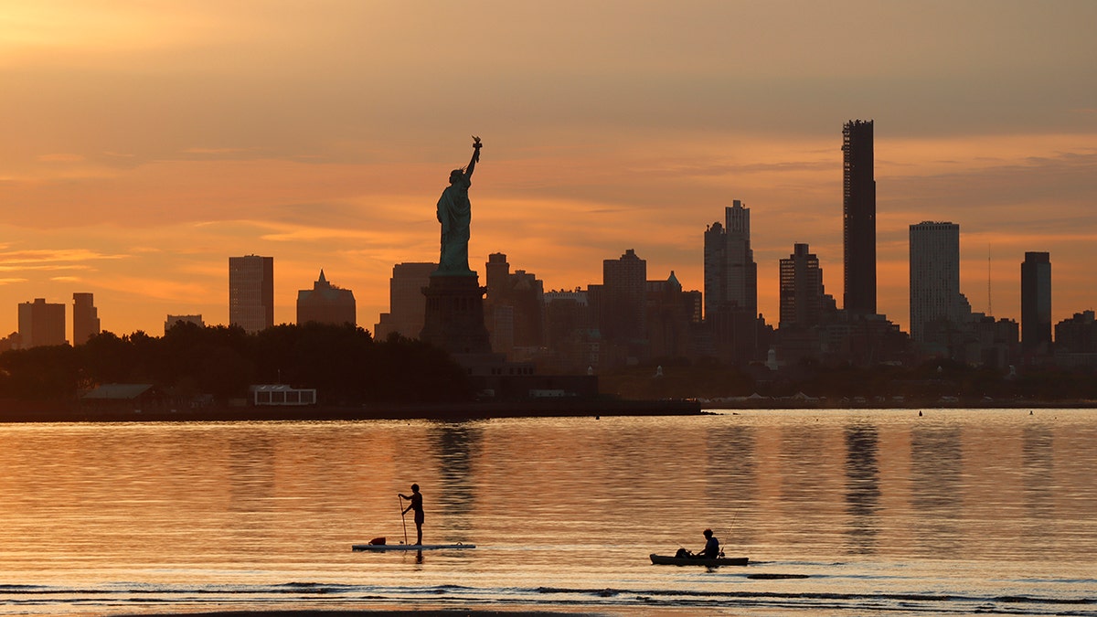 NYC skyline and Statue of Liberty at sunset 