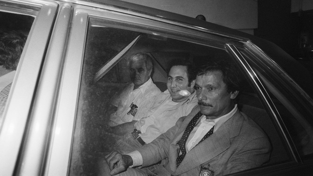 David Berkowitz, 24, (c) sits in police car on August 11, 1977 after his arrest late on August 10, 1977, by detective edward Zigo (r) in connection with the .44-caliber killings. 