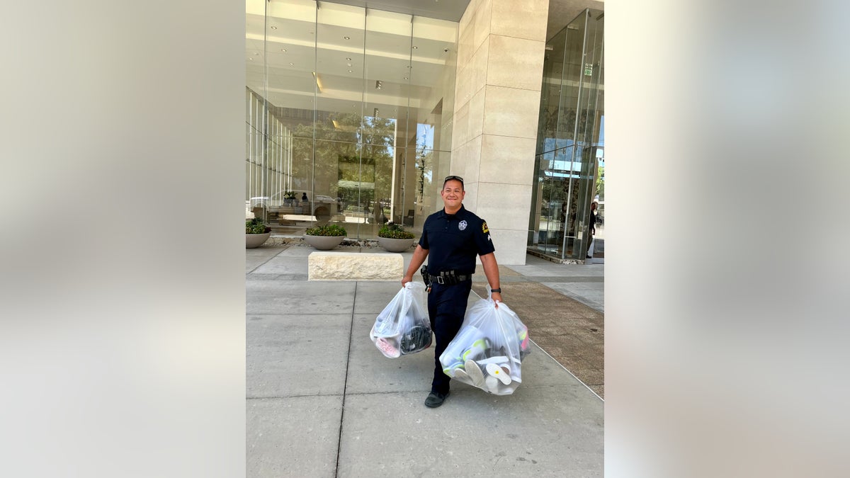 police officer carries bags of shoes to distribute to kids
