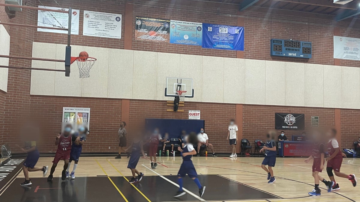 Children in LA are pictured playing basketball while wearing masks