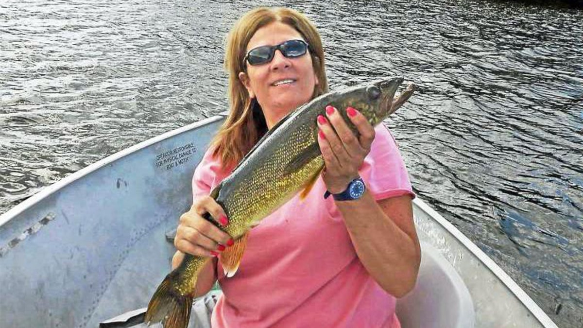 Linda Carman holds a fish wearing sunglasses and pink shirt