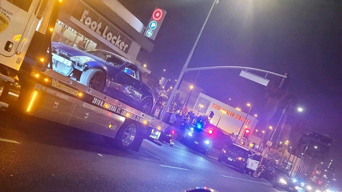 tow truck with a car on top and police vehicles in the street of Los Angeles