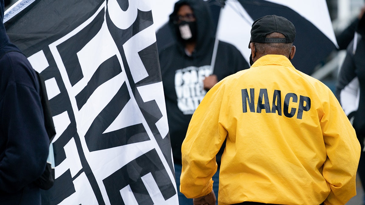 FILE: A man wearing a NAACP jacket walks between demonstrators before a protest march on April 24, 2021, in Elizabeth City, North Carolina.