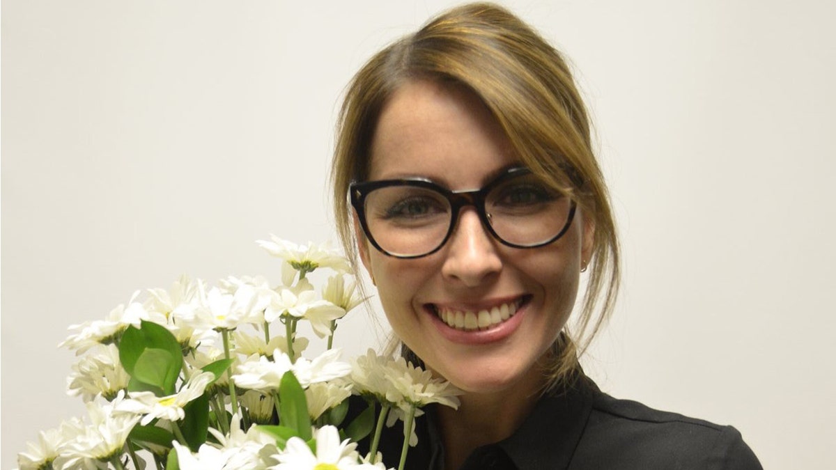 Kathryn Pugh wearing glasses and holding flowers