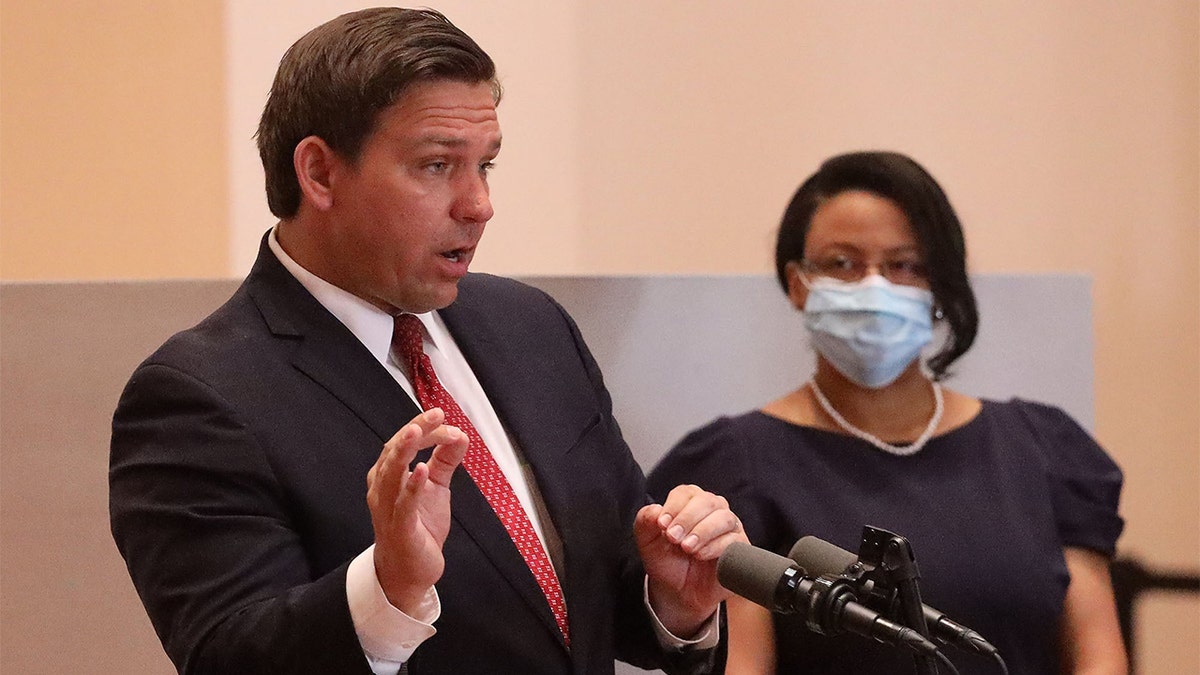 Florida Ron DeSantis speaks at press conference in suit and red tie