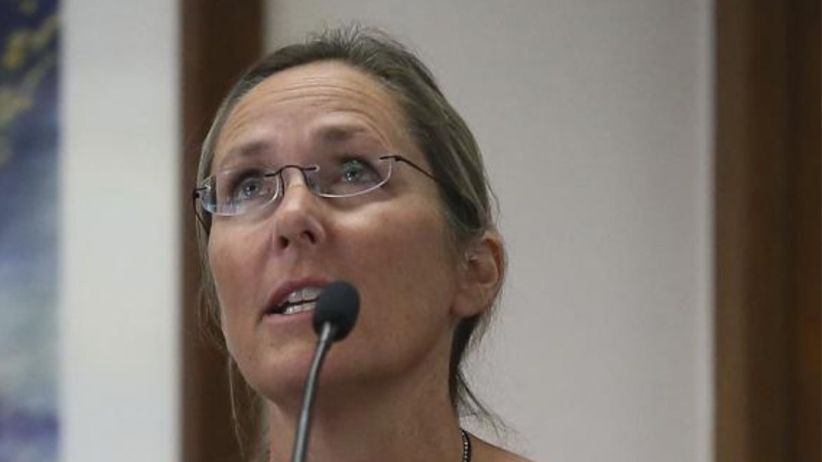 Scarlett Lewis, mother of a Sandy Hook shooting victim, speaks at a microphone wearing glasses
