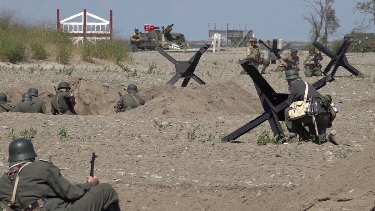 Military reenacts fire guns out of fox holes on Ohio beach made to look like Normandy, France