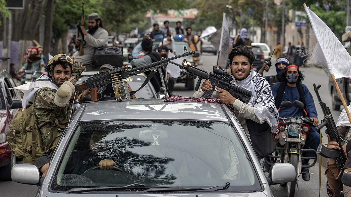 taliban members celebrating in car with weapons