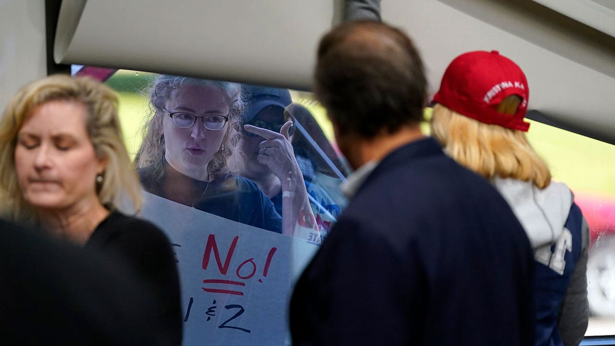 Pro life advocate stands outside of a building, looking in through a window