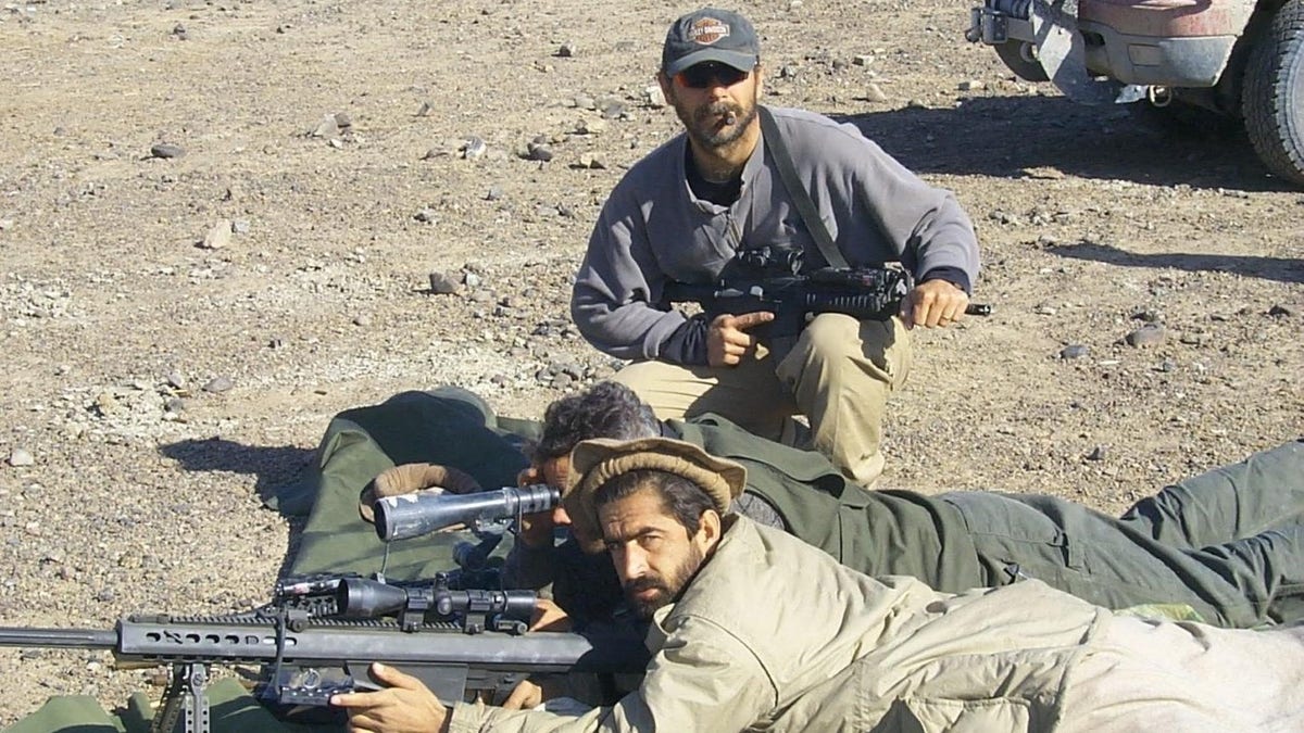 American soldier training Afghan soldier with long rifles