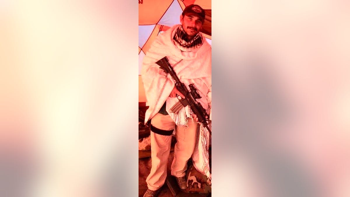 Perry Blackburn dressed in white holding rifle