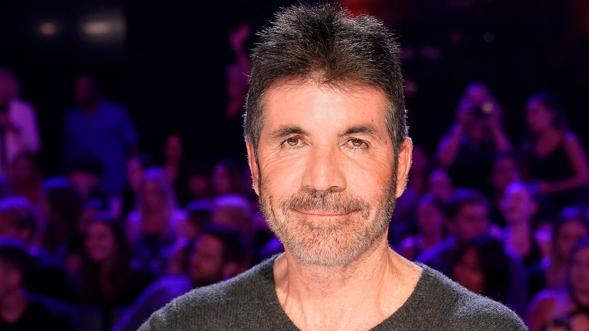 Simon Cowell soft smiles in a black scoop neck on "Amercia's Got Talent"