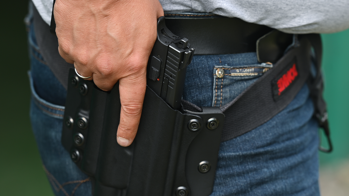 Photo showing man with holstered handgun at shooting range