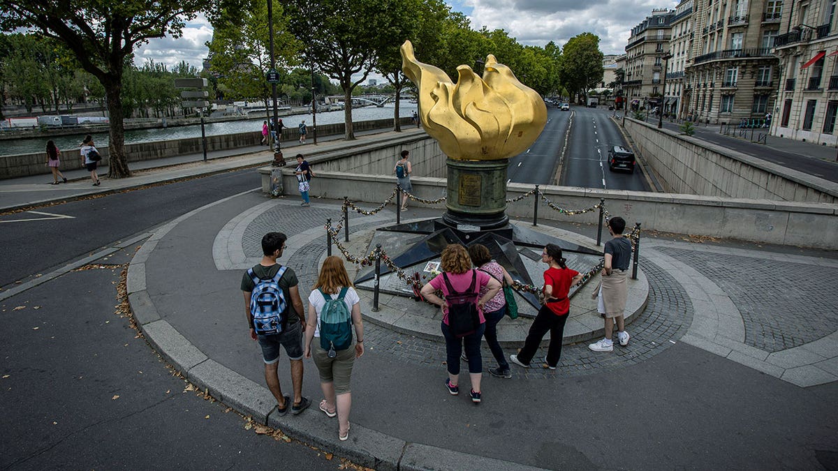 Flame of Liberty in Paris surrounded by tourists on a cloudy day