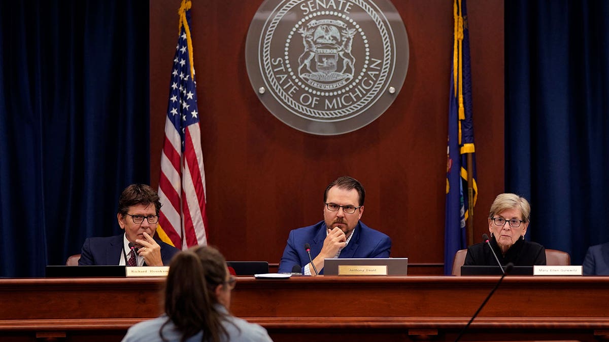 Michigan Board of Canvassers members sit on the bench with the state seal behind them in a courtroom