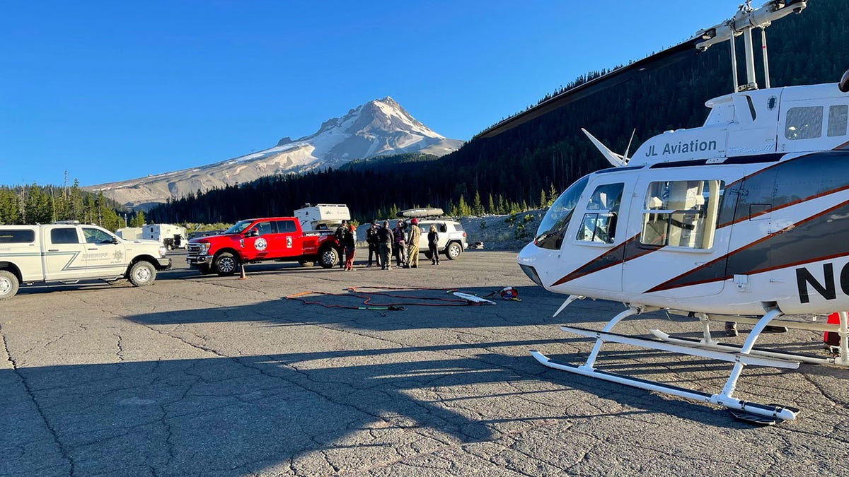 Helicopter and rescuers on ground before Mt. Hood