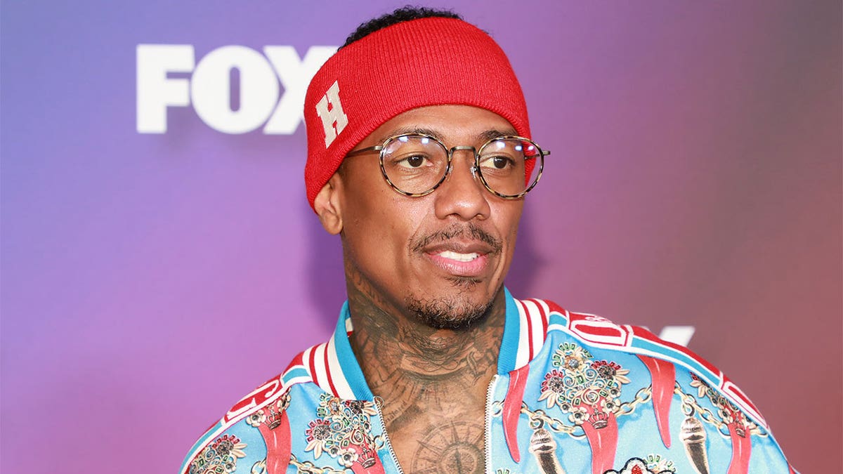 Nick Cannon wearing a red sweat band while arriving at an event