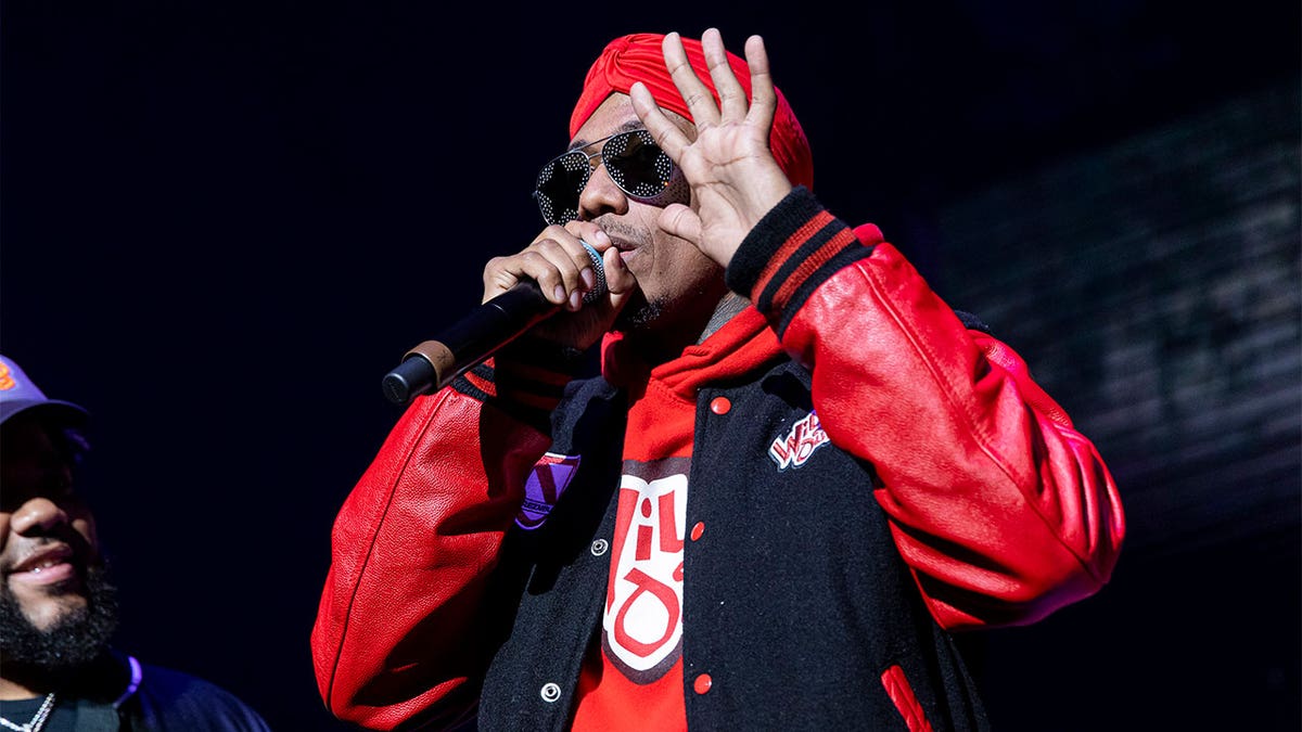 Nick Cannon in a letterman jacket that ihas leather sleeves and a red headband