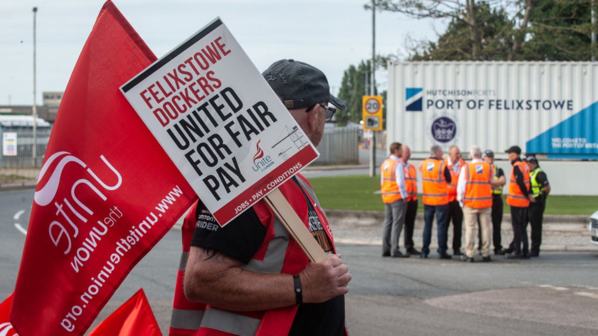 Worker holds sign supporting strike at port