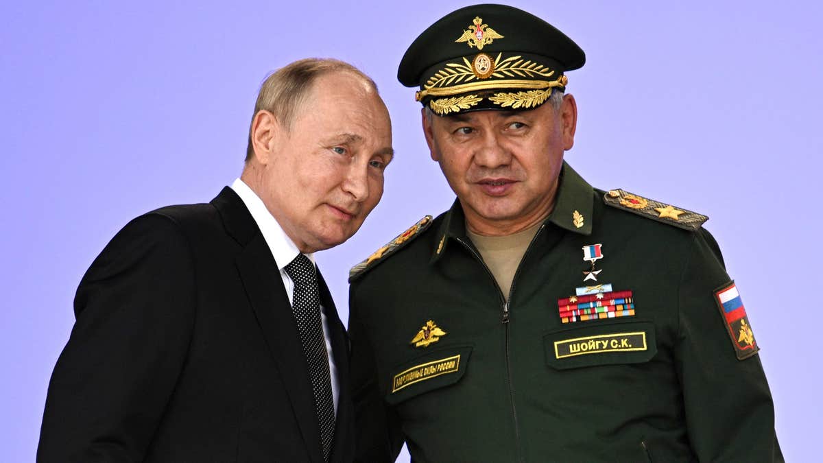 Valdimir Putin stands next to Russian military officer at military forum