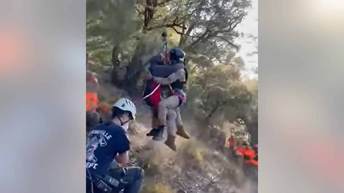 rescuers hoisting mother up to helicopter