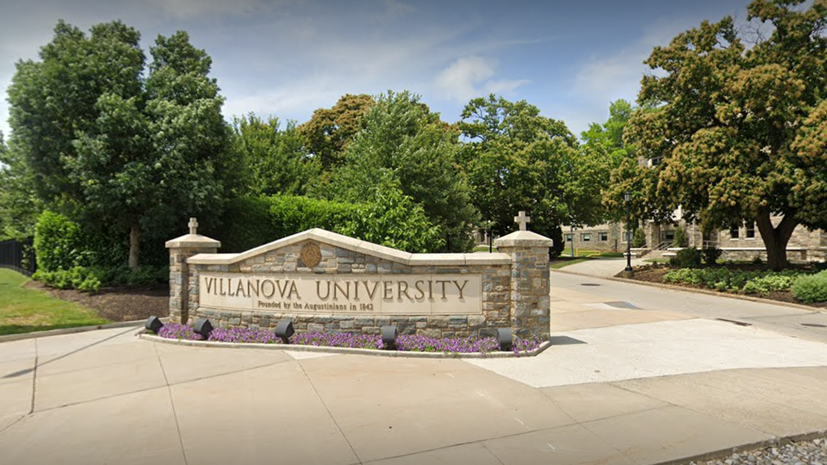 Photo shows Villanova University's entrance with sign in view and trees in the distance 