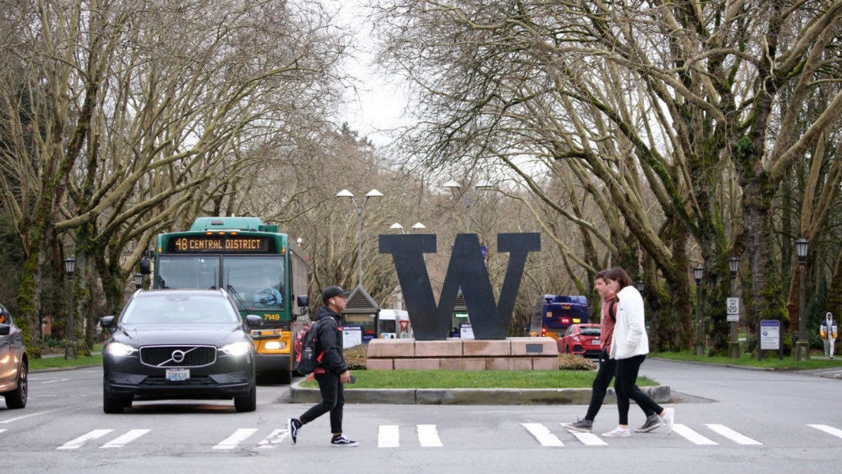 Students walk by the W logo for the University of Washington