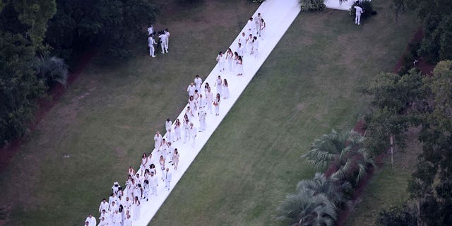 All guests wore white, which is a color typically reserved for the bride, as they are pictured walking down the long aisle.