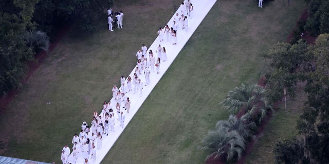 All guests wore white, which is a color typically reserved for the bride, as they are pictured walking down the long aisle.