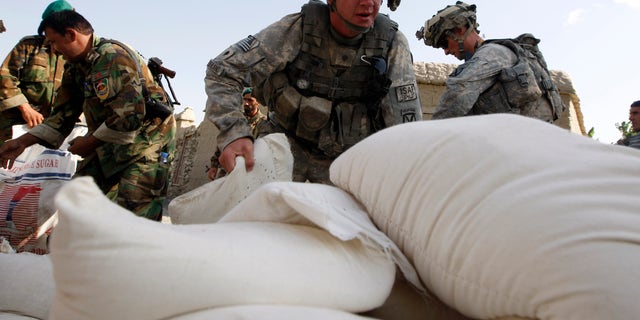 U.S. soldiers from 2nd Platoon, Alpha Company, 32nd Infantry Regiment unload bags of humanitarian aid in the village of Doment, in the Kunar province of Afghanistan, on August 16, 2009.   