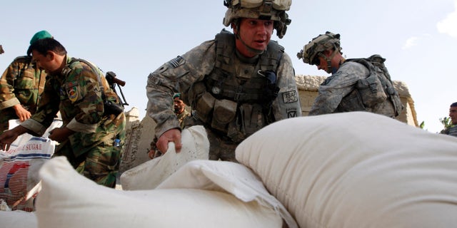 U.S. soldiers from 2nd Platoon, Alpha Company, 32nd Infantry Regiment unload bags of humanitarian aid in the village of Doment, in the Kunar province of Afghanistan, on August 16, 2009.
