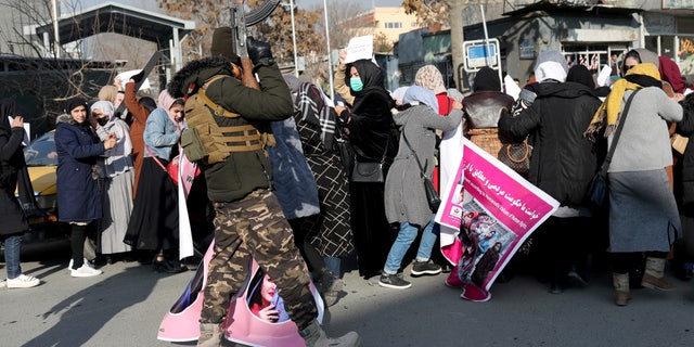 A member of the Taliban forces fires into the air to disperse Afghan women during a demonstration to protest Taliban restrictions on women in Kabul, Afghanistan, December 28, 2021. 