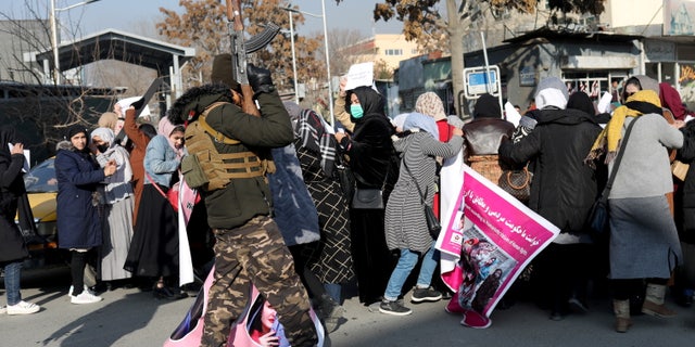 A member of Taliban forces fires into the air to disperse Afghan women during a rally to protest Taliban restrictions on women in Kabul, Afghanistan, Dec. 28, 2021.