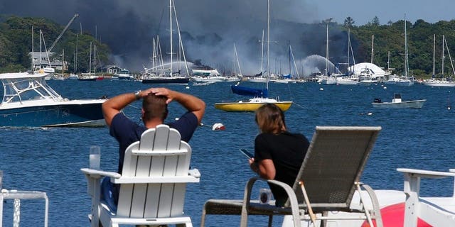 People view a multi-alarm fire as it rips through the Mattapoisett Boat Yard on Ned's Point Road in Mattapoisett, Massachusetts, Aug. 19, 2022.  