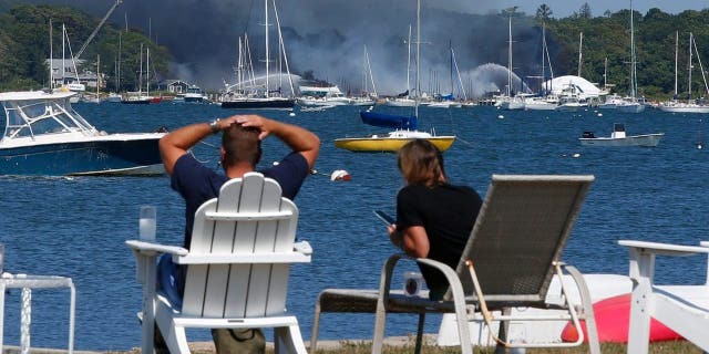People view a multi-alarm fire as it rips through the Mattapoisett Boat Yard on Ned's Point Road in Mattapoisett, Massachusetts, Aug. 19, 2022.