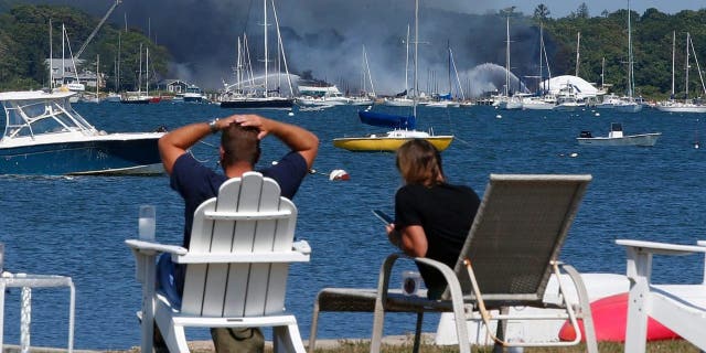 People view a multi-alarm fire as it rips through the Mattapoisett Boat Yard on Ned's Point Road in Mattapoisett, Massachusetts, Aug. 19, 2022.  