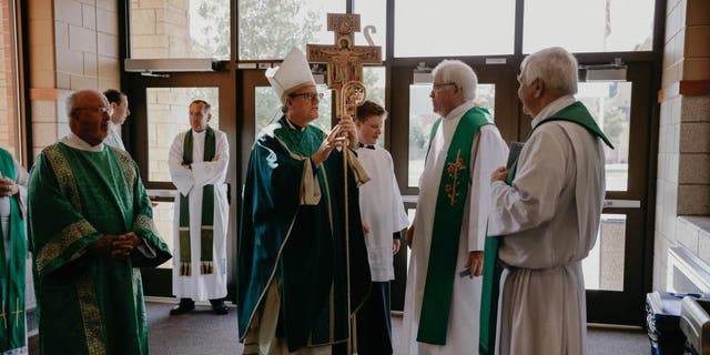 Bishop Barron speaking with priests before mass