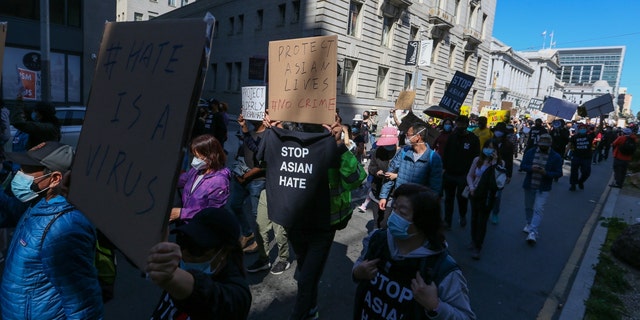 Demonstrators hold up signs as they take part in an anti-Asian American hate march and rally at San Francisco City Hall March 27, 2021. 