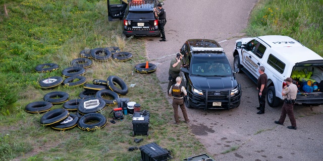 Tubes sit on the bank of the Apple River while Water Recovery authorities comb the area with metal detectors after five people were stabbed while tubing down the river, Saturday, July 30, 2022, in Somerset, Wis. 