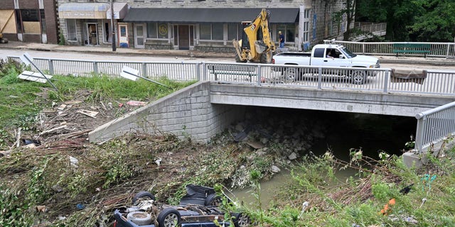 A car lays overturned in Troublesome Creek in downtown Hindman, Kentucky. Now the state will face a heat wave during a pattern of dangerous weather.