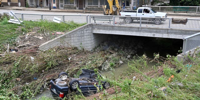 A car lays overturned in Troublesome Creek in downtown Hindman, Kentucky. Now the state will face a heat wave during a pattern of dangerous weather.