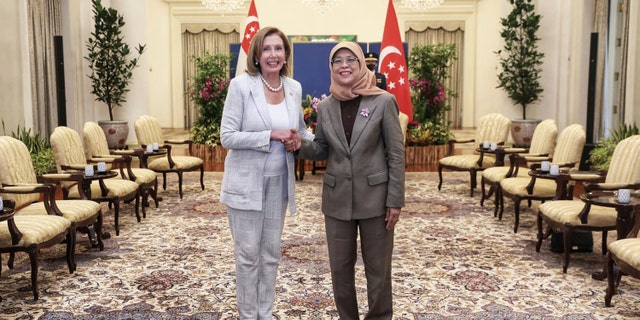 In this photo provided by Ministry of Communications and Information, Singapore, U.S. House Speaker Nancy Pelosi, left, and Singapore President Halimah Yacob shake hands at the Istana Presidential Palace in Singapore, Monday, Aug. 1, 2022. Pelosi arrived in Singapore early Monday, kicking off her Asian tour as questions swirled over a possible stop in Taiwan that has fueled tension with Beijing.
