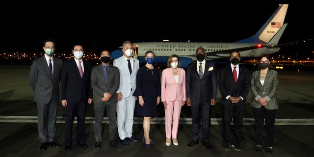 U.S. House Speaker Nancy Pelosi, center, poses for photos after she arrives in Taipei, Taiwan, Tuesday, Aug. 2, 2022.