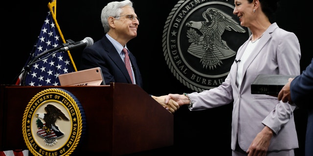 Attorney General Merrick Garland shakes hands with Colette Peters, director of the federal Bureau of Prisons, after she was sworn in at BOP headquarters in Washington, D.C.